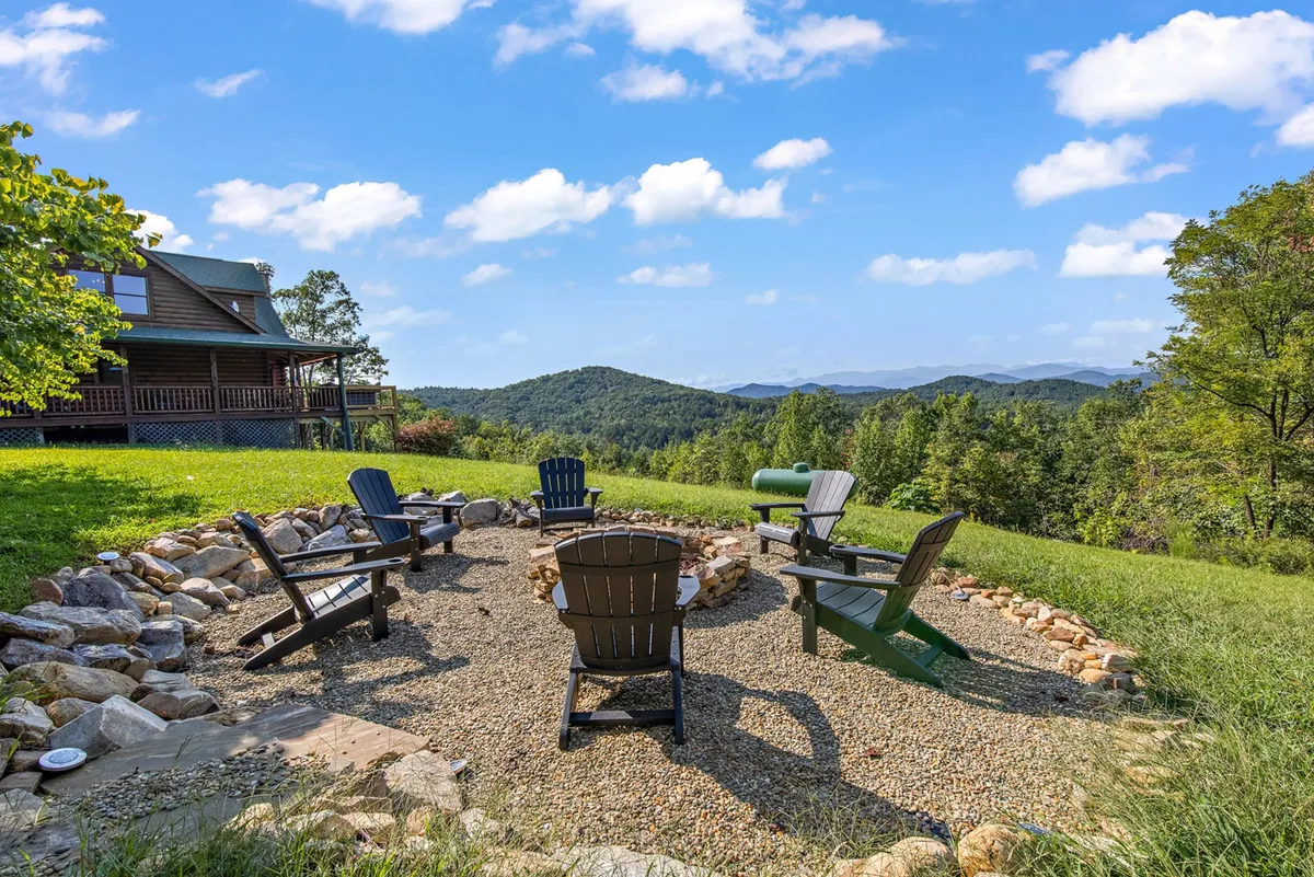 A close-up of the fire pit area with Adirondack chairs facing an expansive mountain view. The scene is intimate and cozy, ideal for campfire gatherings and relaxing with family, friends, or pets after a day of exploring.