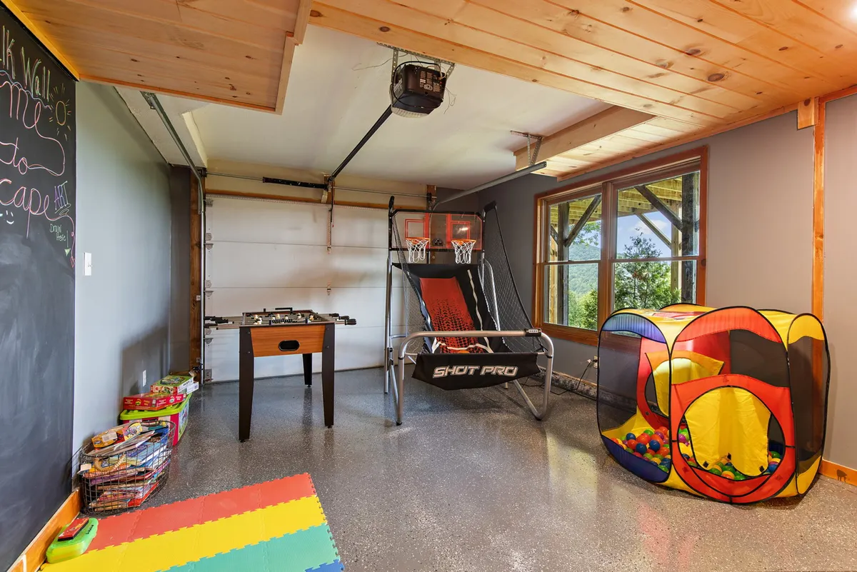 This energetic space highlights a foosball table, a basketball shootout game, a colorful ball pit for children, and a chalkboard wall perfect for creative play. The area is clearly designed for all ages, with activities for both kids and adults in a cheerful, inviting setting.